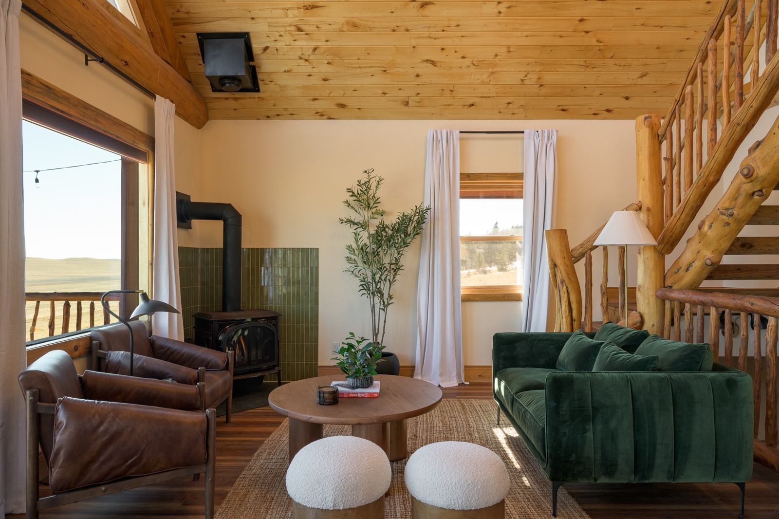 Living room with green velvet sofa, gas stove and log staircase